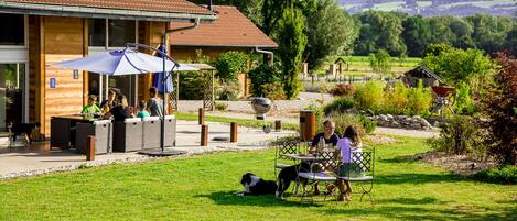 An outdoor dining area with tables and chairs, a covered seating area, and a view of the surrounding landscape.