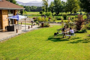 A patio area with outdoor seating, a barbecue grill, and a stone wall. - Paradis (Cornier)