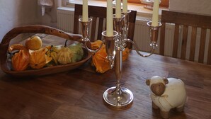 Une table à manger ornée d’un panier de fruits, d’un chandelier avec des bougies et d’une statuette de mouton décorative.