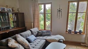 Un salon chaleureux avec un canapé gris, un fauteuil blanc et une bibliothèque.