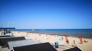 A beach with a lifeguard tower, umbrellas, and beachgoers.