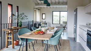 Un espace repas avec une table en bois, des chaises de couleur turquoise et des suspensions turquoise.