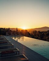 Una piscina al aire libre, sombrillas, sillones reclinables de piscina