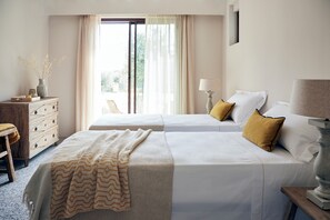 A hotel room with two beds, a wooden dresser, a lamp, and a view of the outdoors through a window. - Borgo 69 (Foiano della Chiana)