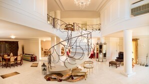 Un vestíbulo espacioso con una imponente escalera, un candelabro y un techo alto.