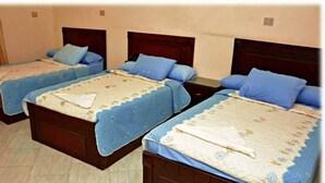 Tres camas individuales con cabeceros de madera, cada una con colcha y almohadas azules a juego.