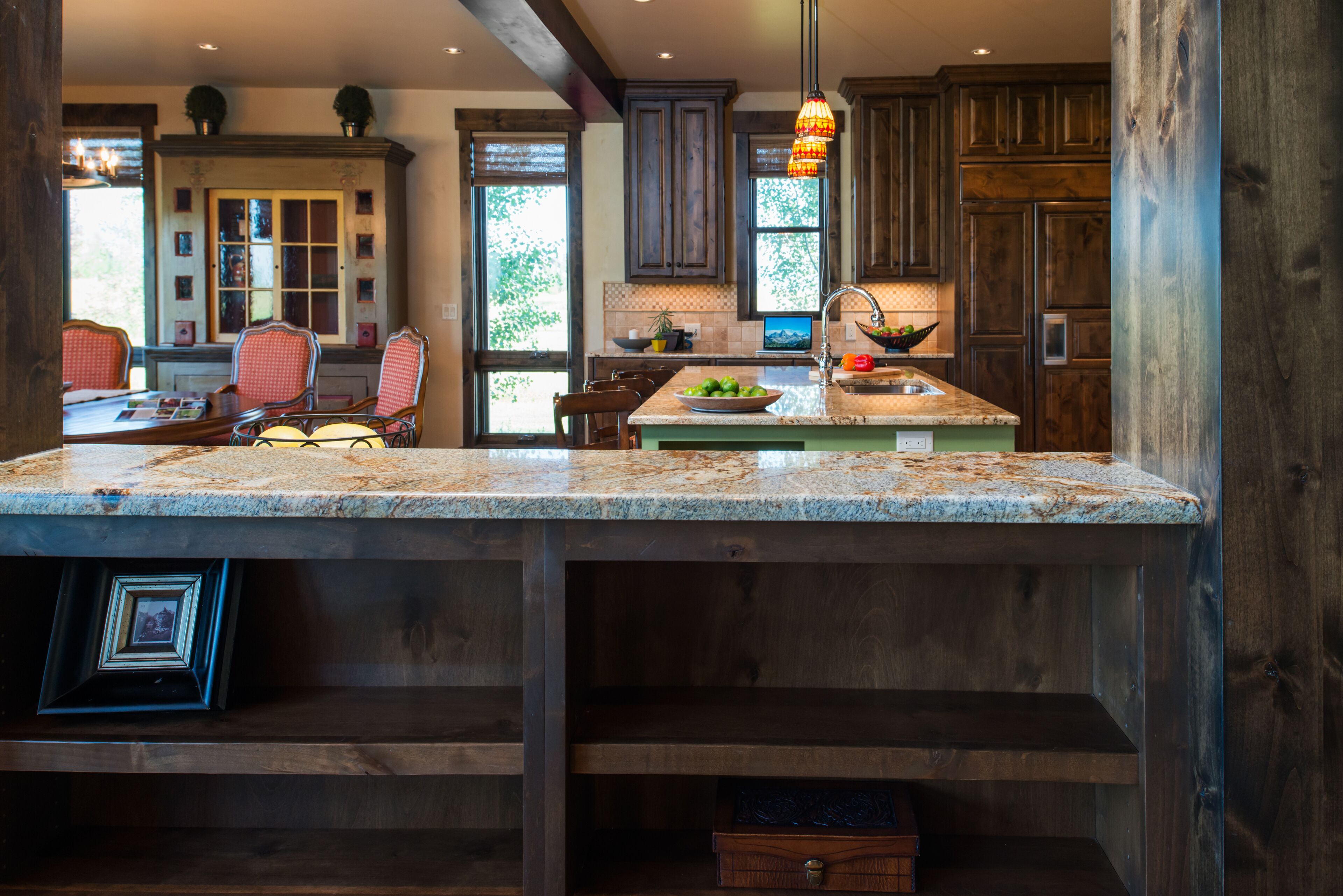 A spacious kitchen with wooden cabinets, a granite countertop, and a hanging pendant light.