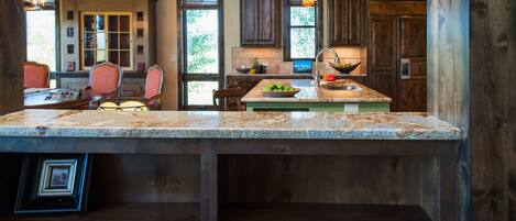 A spacious kitchen with wooden cabinets, a granite countertop, and a hanging pendant light.
