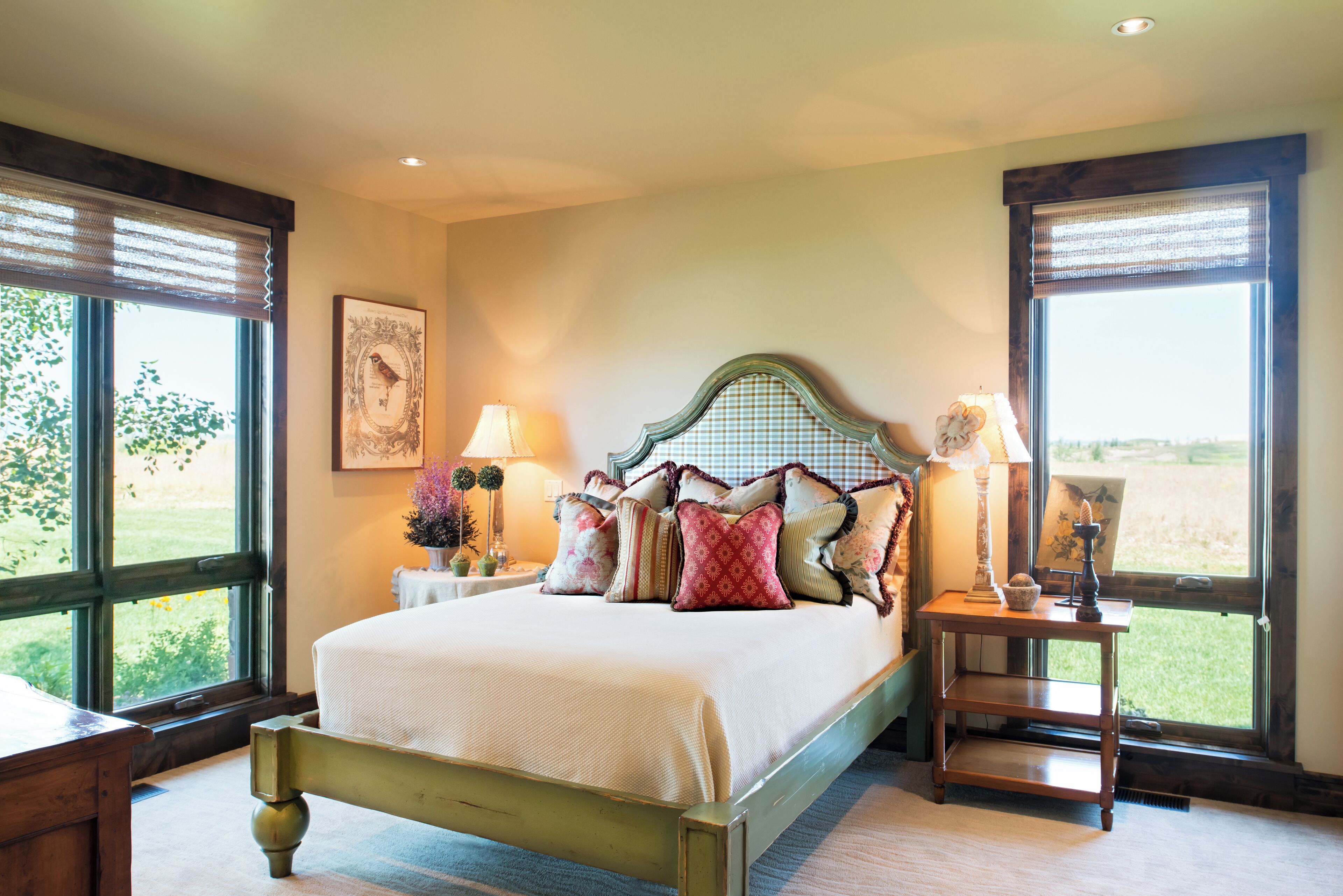 A bedroom with a bed, bedside tables, and a view of the outdoors.