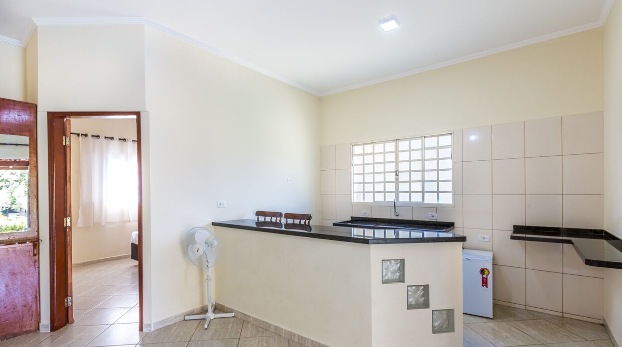 A kitchen with a built-in stove, a small refrigerator, and a window with blinds.