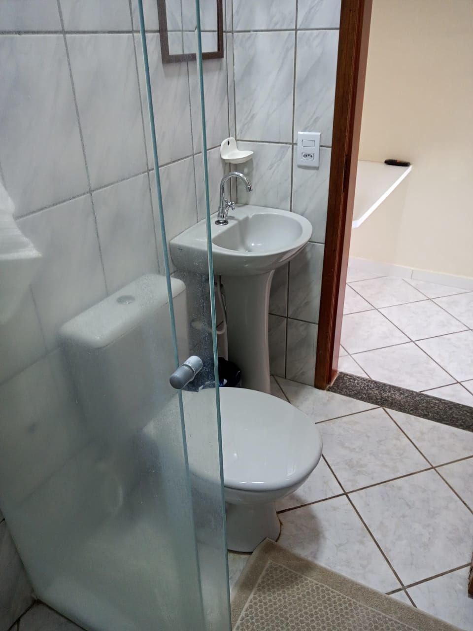 Een badkamer met toilet, wastafel en douchecabine met glazen wanden.