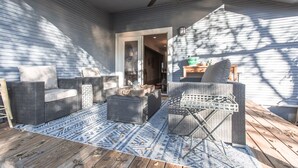 Een overdekt terras met rieten meubilair, een plafondventilator en uitzicht op het huis.