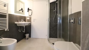 Uma casa de banho moderna com cabine de duche em vidro, lavatório e sanita.