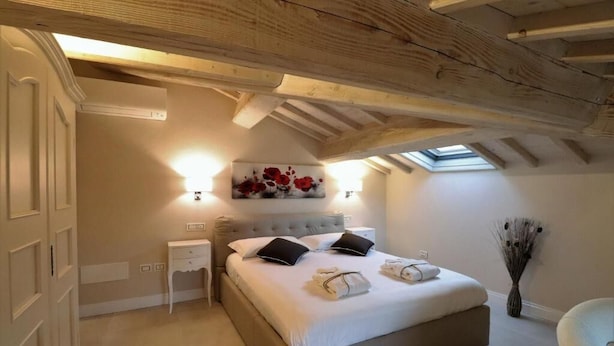 Quarto com cama grande, mesa de cabeceira, obra de arte na parede e claraboia.