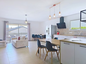 A modern kitchen with a dining area, a sofa, and a view of the outside.