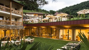 Un hotel con un salón cubierto de vidrio, asientos al aire libre y vistas del paisaje circundante.