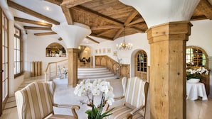 Amplio espacio interior con techos altos, vigas de madera y una escalera central que conduce a una zona de recepción.