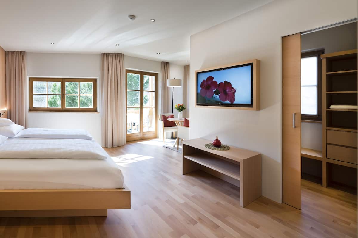 A modern hotel room with a large bed, bedside tables, a desk, and a TV.