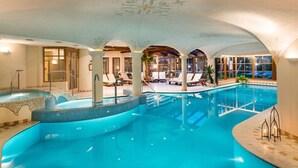 Una piscina interior de diseño curvo, con zonas de descanso y vistas al exterior.