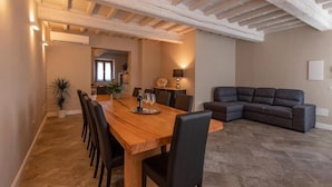 Un comedor con una mesa y sillas de madera, un sofá de cuero oscuro y una cocina moderna al fondo.