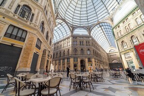 Ein geräumiger Innenhof mit hohen Decken und einer Glaskuppel, der sich durch kunstvolle Architektur und Sitzbereiche auszeichnet.