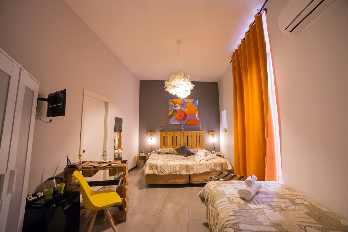 Ein Schlafzimmer mit einem Bett, einem Schreibtisch, einem Stuhl und einem kleinen Tisch mit einer Lampe.