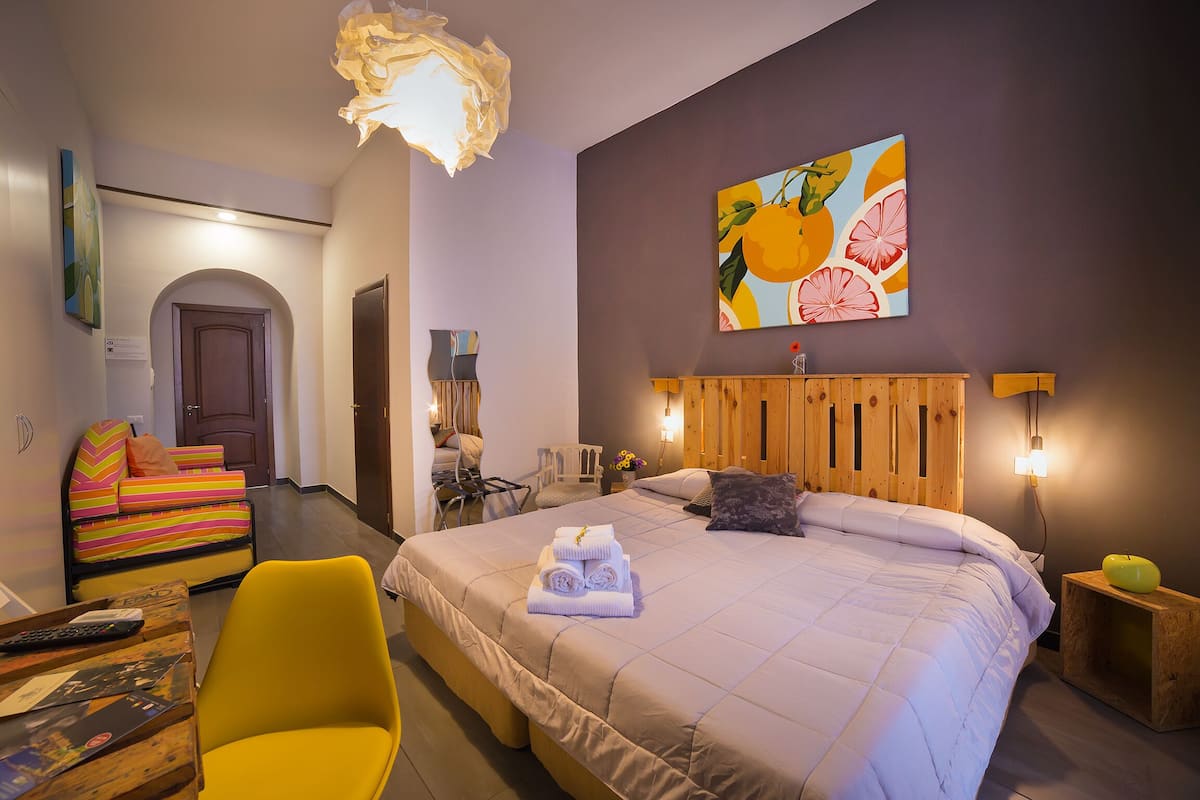 Ein Schlafzimmer mit einem großen Bett, einem Holzkopfende, einem Bild an der Wand und einem gelben Sessel.