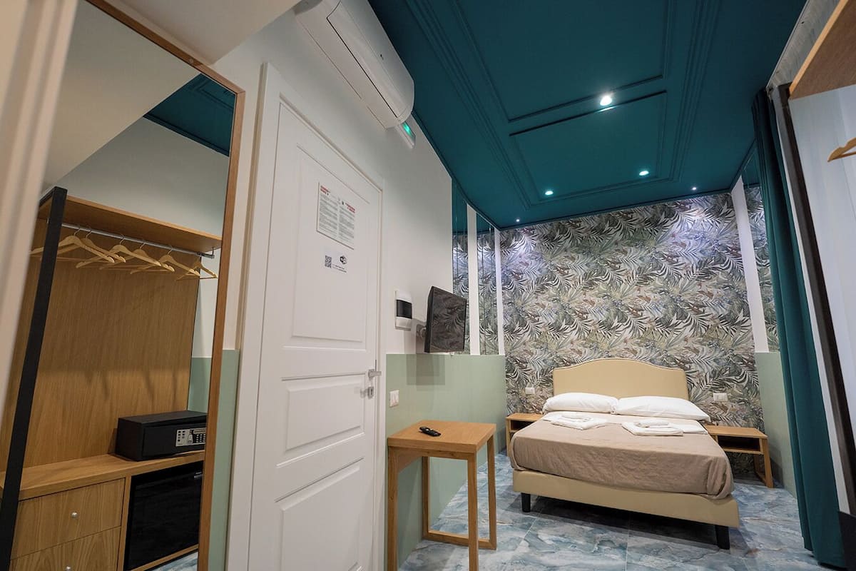 Ein Hotelzimmer mit einem Bett, einem kleinen Tisch, einem Kleiderschrank und einem Spiegel.