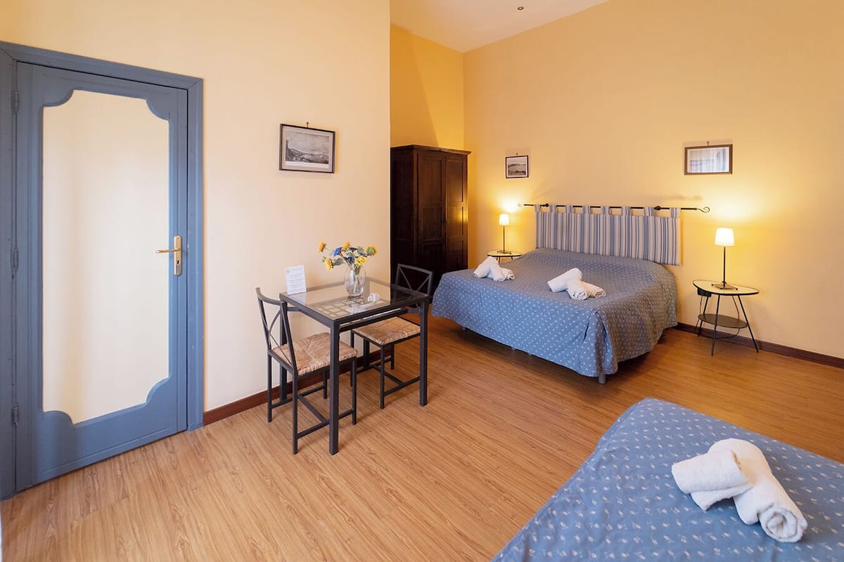 Ein Hotelzimmer mit Bett, Schreibtisch mit Stuhl, kleinem Tisch mit Lampe und Kleiderschrank.