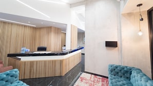 Una zona de recepción moderna con un mostrador de madera, una encimera de mármol negro y una butaca tapizada en azul.
