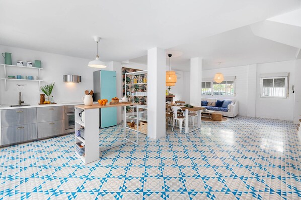 A modern kitchen with a teal refrigerator, white cabinets, and a blue and white patterned floor. - Chuita - Holiday rental Pedregalejo (Málaga)