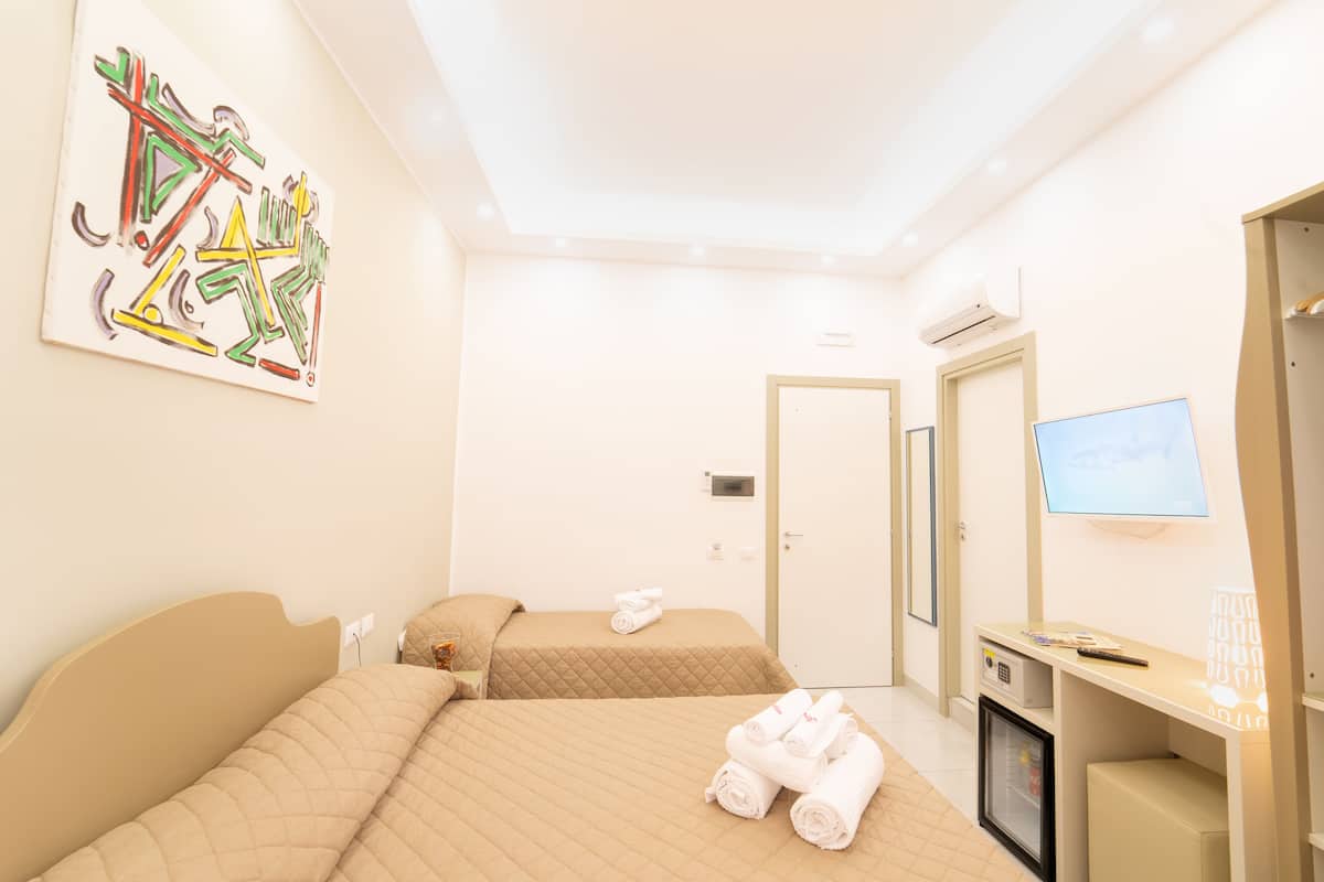 A hotel room with two beds, a television, a desk, and a minibar.