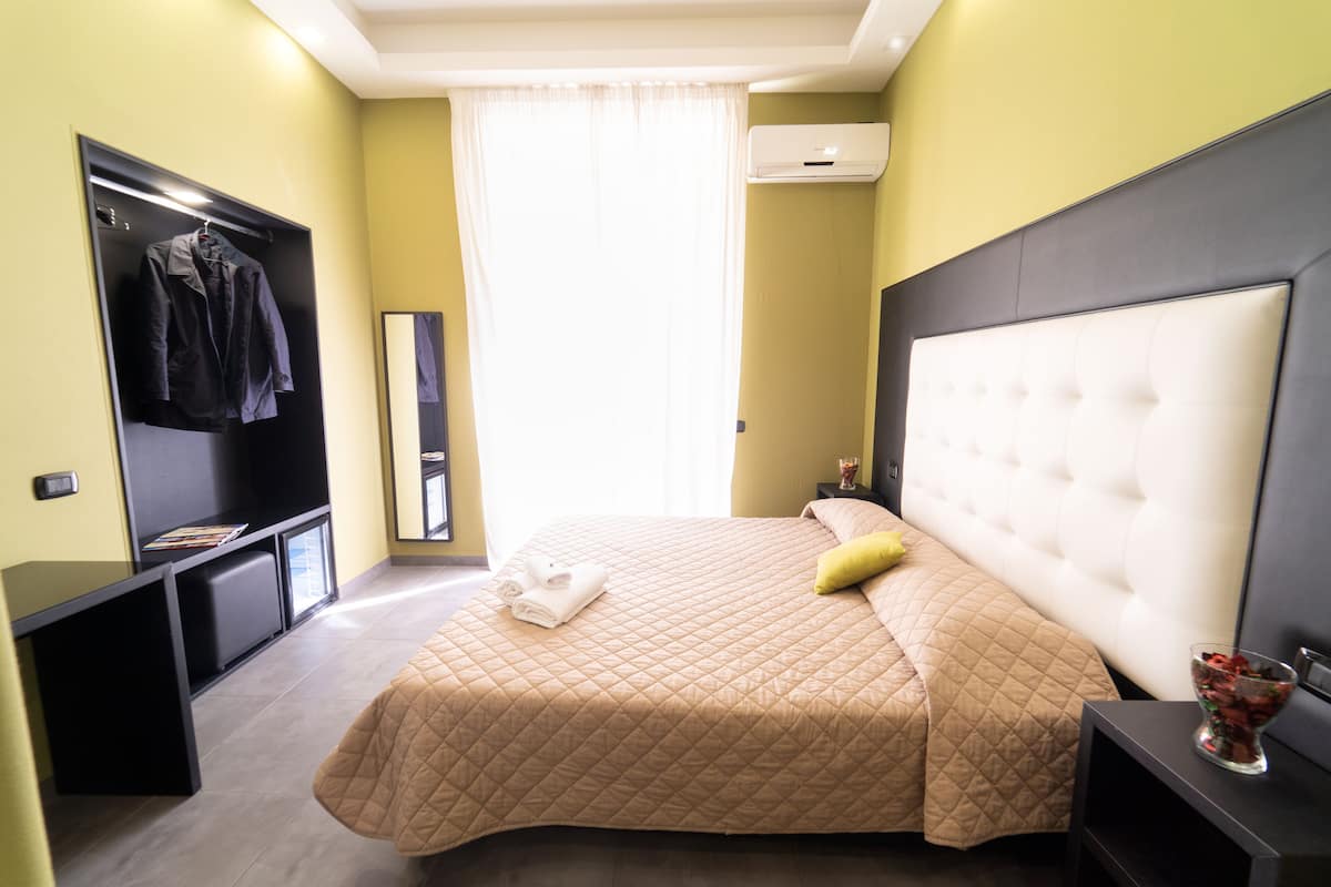 A hotel room with a bed, a TV, a wardrobe, and a bedside table.