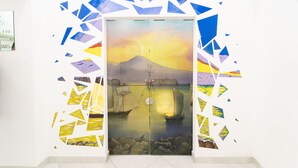 A door with a painting of a sunset over water, surrounded by geometric shapes. - Royal Art H Spaccanapoli by ClaPa Group Dislocated Hospitality (Naples)