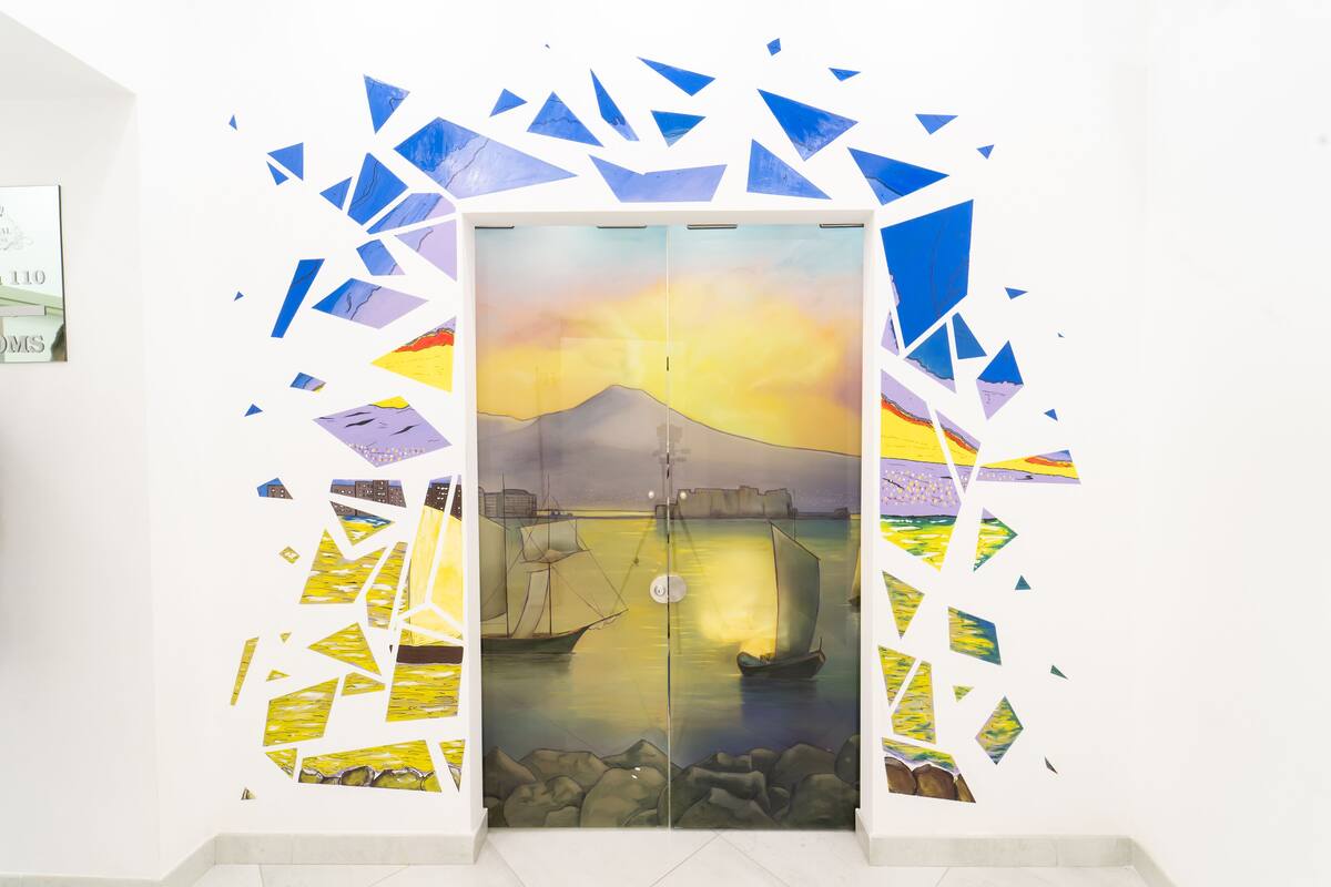 Uma porta com uma pintura de um pôr do sol sobre a água, cercada por formas geométricas.