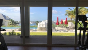 A room with a view of a pool, outdoor seating, and exercise equipment. - Luxury Condo with spectacular amenities on Paradise Island (Paradise Island, Nassau)