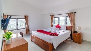 A hotel room with a bed, bedside table, lamp, and curtains. - A Bong Villa (Da Nang)