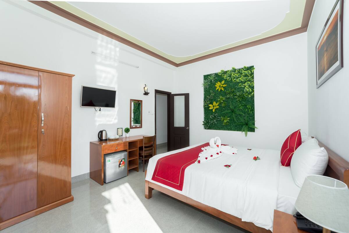 A hotel room with a bed, wardrobe, desk, and a television.