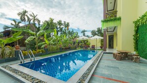 A rectangular swimming pool with a tiled edge, surrounded by a stone border. - A Bong Villa (Da Nang)