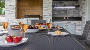 Ein Essbereich im Freien mit Backsteinmauer, integriertem Grill und moderner Küche.