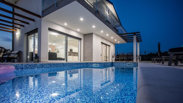Ein modernes Gebäude mit Pool, großen Glasfenstern und einem Balkon.