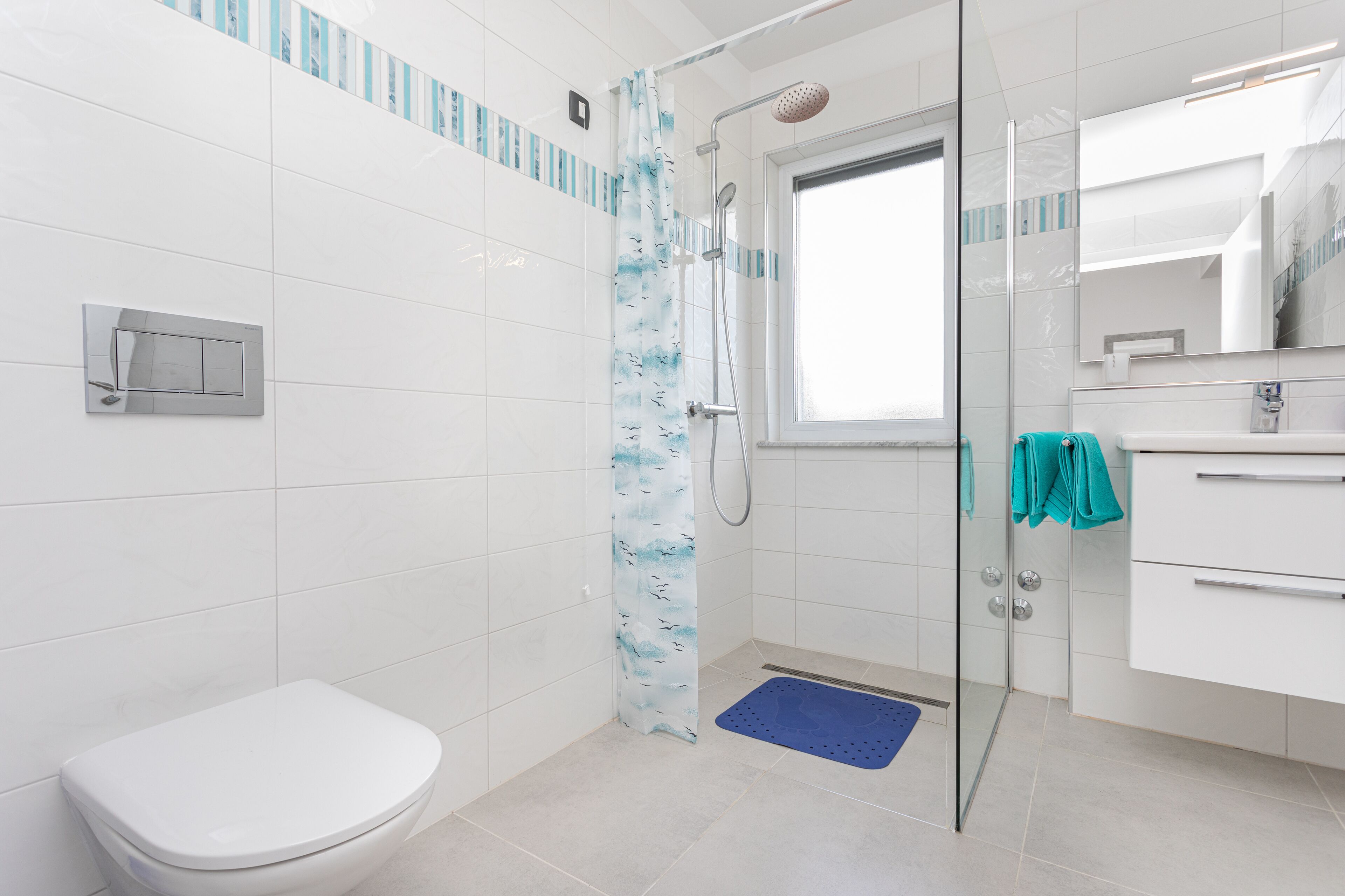 A modern bathroom with a glass shower enclosure, a white toilet, and a blue mat.