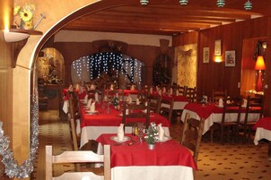 Un restaurante con manteles rojos, sillas de madera y un ambiente festivo.
