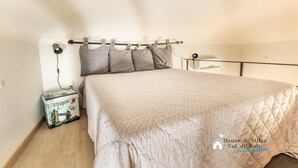 A bedroom with a bed, a nightstand, a lamp, and a suitcase.