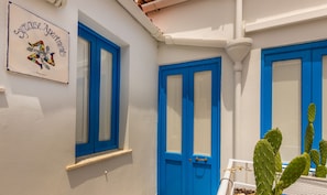Stylish Syracuse Apartments feature a charming blue door and white exterior, complete with a small potted cactus.