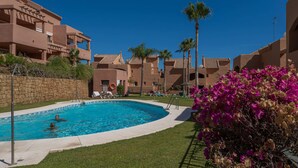A swimming pool surrounded by a poolside area with lounge chairs and palm trees. - SUPERB APARTMENT WITH SEA VIEW AND ELVIRIA GOLF COURSE (Marbella)