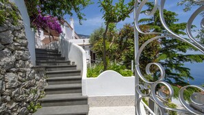 A staircase with stone steps leading up to a white building with a view of the sea. - Casa Albatros (Praiano)
