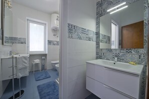 A bathroom with a white sink, a mirror, and patterned tiles.