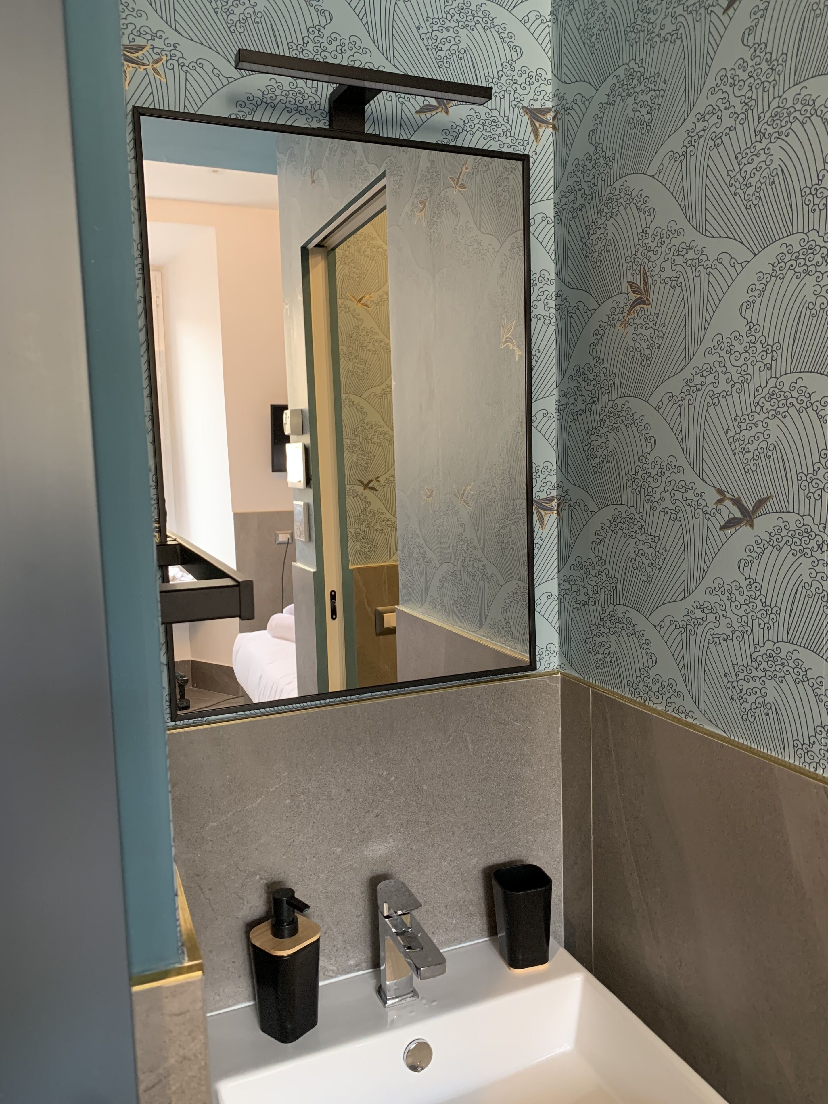 A bathroom with a large mirror, a sink, and a towel rack.
