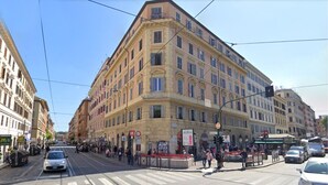 A corner building with multiple floors, large windows, and a street in front. - Ottaviano Smart Rooms (Rome)